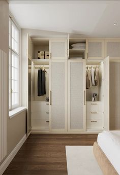 an empty bedroom with white closets and wood flooring on the walls, along with a large bed