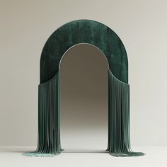 an arch shaped mirror with tassels on the front and sides, in green velvet