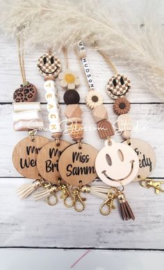 wooden keychains with personalized name tags and charms attached to them on a white wood background