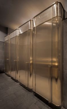 a row of shiny metal stalls in a public restroom