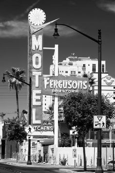 a black and white photo of a motel sign with palm trees in the foreground