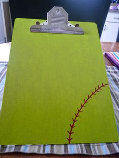 a clipboard with a baseball stitching on it sitting on top of a table