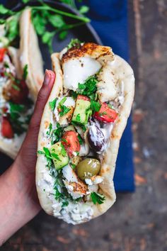 a hand holding a pita filled with vegetables