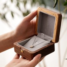 a person holding an open wooden box with a necklace in it