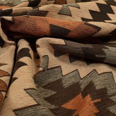 the fabric is made up of many different colors and shapes, including black, brown, tan, and orange