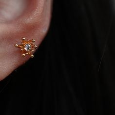 a close up of a person's ear with a diamond in the shape of a flower