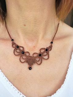 a woman wearing a brown necklace with black beads on her neck and an intricate design