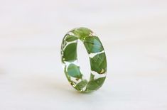 This ring features real pressed clover leaves, delicately preserved in resin, and adorned with elegant silver, gold, or copper flakes.  Width: 5 mm/0.19 in Thickness: 2 mm/0.07 in Matching necklace → https://www.etsy.com/listing/1561821312 Matching bracelet → https://www.etsy.com/listing/1589060099 The order may include a gift message and wrapping. If you have any questions, please feel free to contact me. More designs of rings: https://www.etsy.com/shop/livinlovin?section_id=15485611&ref=shopse Nature-inspired Green Jewelry With Pressed Flowers, Pressed Clover, Clover Leaves, Faceted Ring, Resin Ring, Nature Inspired Jewelry, Matching Bracelet, Gold Copper, Inspired Jewelry