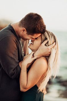 a man and woman embracing each other by the ocean