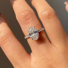 a woman's hand with a diamond ring on top of her finger and the other hand holding an engagement ring