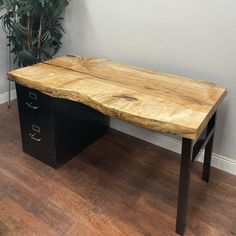 an office desk made out of wood and black metal drawers with a potted plant in the corner