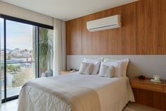 a bed with white sheets and pillows in a bedroom next to a large sliding glass door