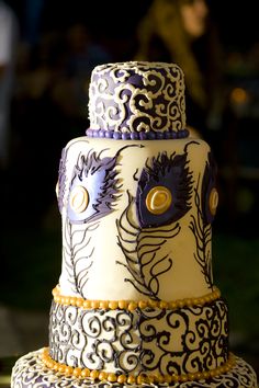 a three tiered cake decorated with blue and white designs on it's sides