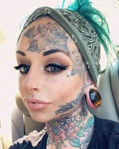 a woman with green hair and tattoos on her head is sitting in the back seat of a car