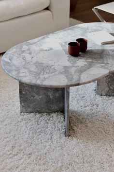 a marble coffee table sitting on top of a white carpeted floor next to a couch