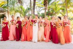 a group of women standing next to each other on top of a sandy beach covered in palm trees