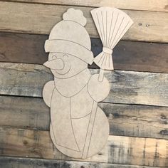 a paper cut out of a snowman holding a fan on top of a wooden wall