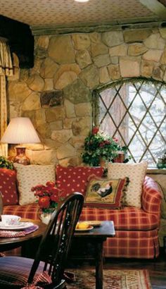 a living room filled with furniture next to a stone wall covered in flowers and greenery