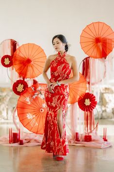 a woman in a red dress standing next to orange umbrellas