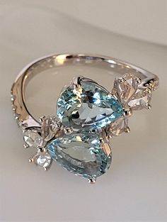 You are purchasing a CJ Jeweler 14K White Gold Aquamarine Diamond Cocktail Rig. This gorgeous ring is crafted in 14k white gold and features 2 sparkling eye clean faceted pear aquamarines, accompanied by 6 pear diamonds set in crossover flower motif and there're additional 10 round brilliant diamonds bezel set on the band. Each aquamarine measures about 9x7mm and each pear diamond is 4x2mm. The total weight of the gemstones is about 3.93 carats. The face of the ring is about 20x15mm the band wid Aquamarine Cocktail Ring, Sparkling Eyes, Diamond Cocktail Ring, Diamond Cocktail Rings, Flower Motif, Aqua Marine, Old Jewelry, Pear Diamond, Bezel Diamond