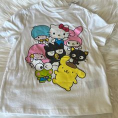 a t - shirt with cartoon characters on it sitting on a white bedding sheet