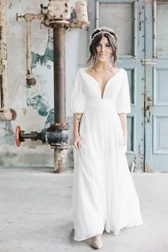 a woman wearing a white dress standing in front of an old building with blue doors