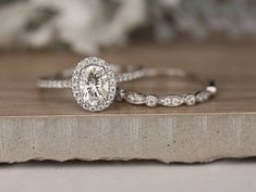 two wedding rings sitting on top of a wooden table next to a white flower arrangement