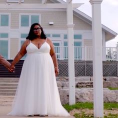 a man and woman holding hands in front of a house