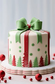 a decorated christmas cake sitting on top of a white table with red and green decorations