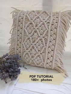 a crocheted pillow sitting on top of a table next to lavender flowers and a piece of paper