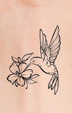 a small tattoo on the back of a woman's stomach with a hummingbird and flowers