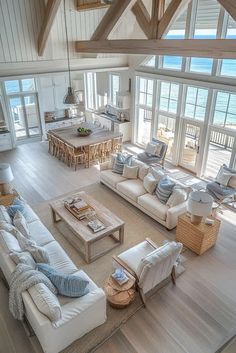 a living room filled with lots of furniture next to an open floor plan and large windows