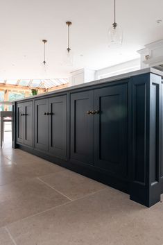 an empty kitchen with black cabinets and marble flooring