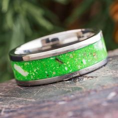 a green and silver ring sitting on top of a rock