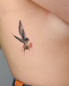 a small bird on the side of a woman's stomach with flowers in it