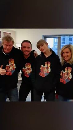 a group of people standing next to each other in front of a window wearing t - shirts