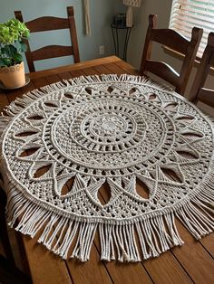 a crocheted doily sits on a wooden table with two chairs and a potted plant in the background