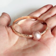 Adorable heirloom bangle for your princess is make with decorative floral pattern wire and genuine pink Edison pearl. Bangle is hand- formed, hammered and polished for a stunning texture and shine. It looks great worn alone or paired with other shell and charm bangles to create a chic, fun beachy look. Pink Edison pearl is 10-11 mm. Bangle is about 4mm wide and 1.5 in thickness. For engraving inside bangle: https://etsy.me/2H0W6C3 As you can see in the photos there are naturally occurring blemis Elegant Pink Pearl Bangle Bracelet, Pearl Bangle Jewelry Gift, Pearl Bangle Jewelry As Gift, Feminine Wedding Jewelry Bangle, Delicate Pink Pearl Bracelet For Wedding, Pearl Bangle As Gift, Pink Bangle Cuff Bracelet For Wedding, Pink Round Cuff Bracelet For Gifts, Bangle Jewelry For Bridesmaid Gift