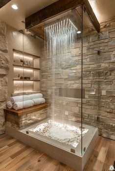 a bathroom with stone walls and flooring has a large glass shower head in the corner