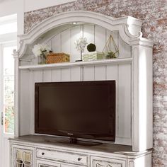 a white entertainment center with a flat screen tv on it's stand and shelves