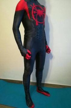 a man in a spider - man suit standing next to a white wall and blue carpet