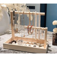 a wooden jewelry box with necklaces and watches in it sitting on a table next to flowers