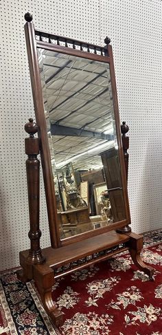 an antique mirror sitting on top of a wooden stand next to a red rug and white wall