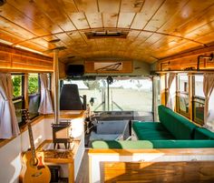 the interior of an rv with green couches and wood paneling on the walls