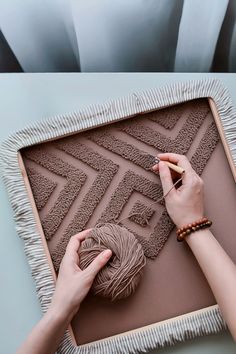 a woman is working on an art project with yarn and cotton in front of her