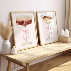 two framed pictures with drinks in them sitting on a wooden table next to a vase