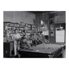 an old black and white photo of men playing pool in a room full of books