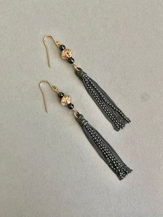 This pair of earrings will complete so many of your outfits!  What great earrings for a dressy outfit.   They hang and move beautifully. These beads are really special.   They are gold filled but they look like they are gold.  I have set an hematite bead on either side to show off the bead and compliment the tassel.   The tassel is so gorgeous.   It is oxidized sterling silver.   All the beads move separately.  Every piece swings separately so there is alot of movement in the earrings.  *Total length of the earrings is approx 3 5/8" *width of bead 3/8" *depth of bead 1/4" *Gold filled French ear wires These earrings can be used for everyday, wearing to work, parties or bridesmaid gifts.   If you are interested in multiple pair for bridesmaids please contact me. Work Parties, Earring Inspiration, Dressy Outfit, Holiday Wear, Earrings Inspiration, Hematite Beads, Black Earrings, Fort Collins, Oxidized Sterling Silver