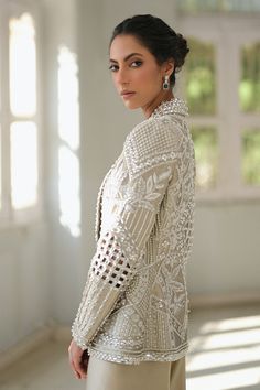 A slate coloured tissue jacket with folded lapels is rendered with intricate cutwork and thread and embroidery. Paired with ivory choli and slate-coloured charmeuse box trousers with embroidered hems; this outfit exudes sheer elegance. Model Height is 5'6 jacket length is 26" Indian Suit With Jacket, Elegant Cream Sherwani With Intricate Embroidery, Elegant Embellished Nehru Jacket With Long Sleeves, Elegant Silk Sherwani With Resham Embroidery, Elegant Silk Sherwani With Intricate Embroidery, Elegant Silk Nehru Jacket, Elegant White Bandhgala With Pearl Embroidery, Elegant Evening Sets With Intricate Embroidery, Glamorous Formal Sets With Pearl Embroidery