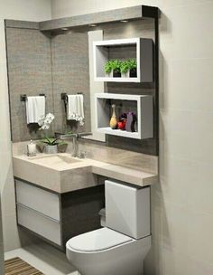 a white toilet sitting next to a sink in a bathroom under a mirror above it